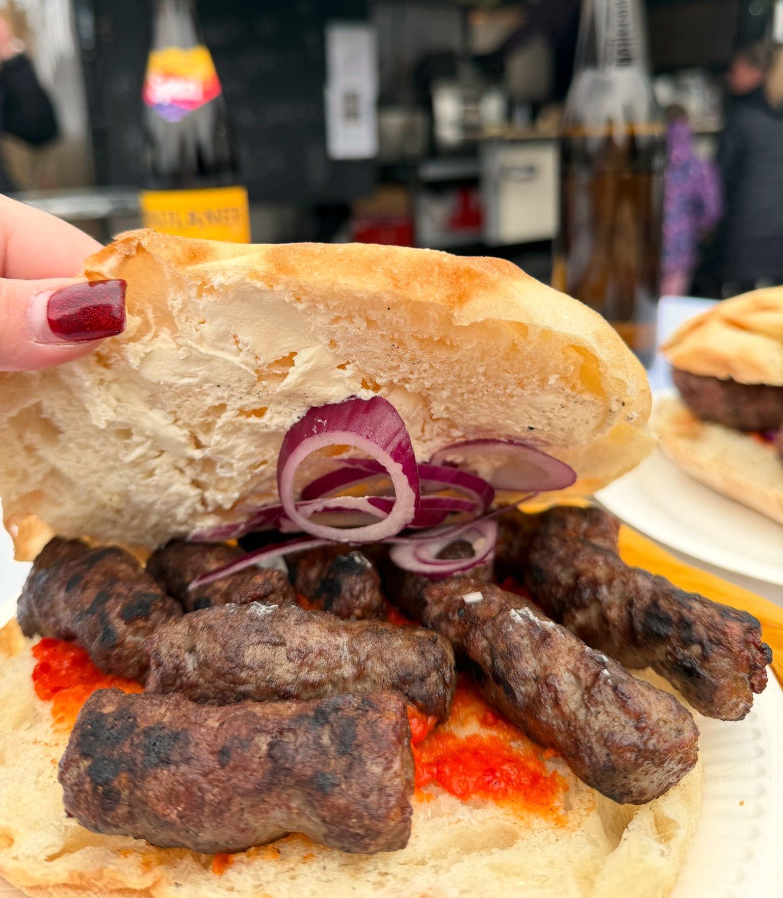 Ćevapčići im Fladenbrot mit Kajmak, Ajvar und roten Zwiebeln